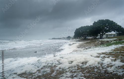 Obraz na płótnie Strong winds send sea foam flying to the beach. Milford Beach. Auckland. w salonie