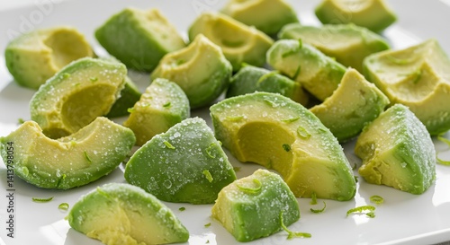 Frozen avocado chunks, covered in ice condensation, spread out on a sleek white tray.