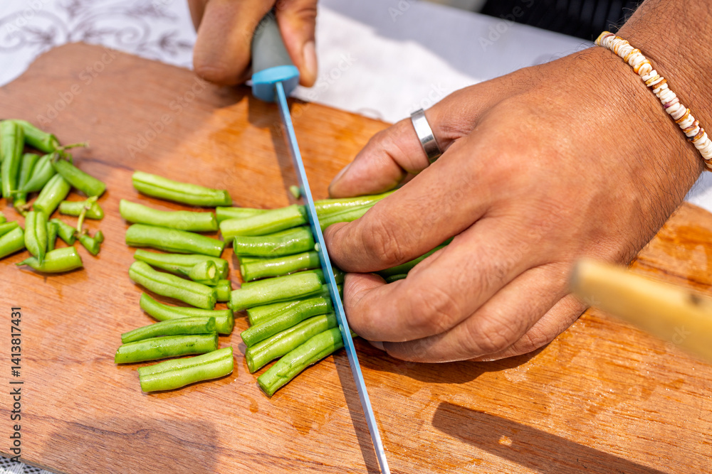 Obraz premium Chef chopping green beans on wooden cutting board for paella