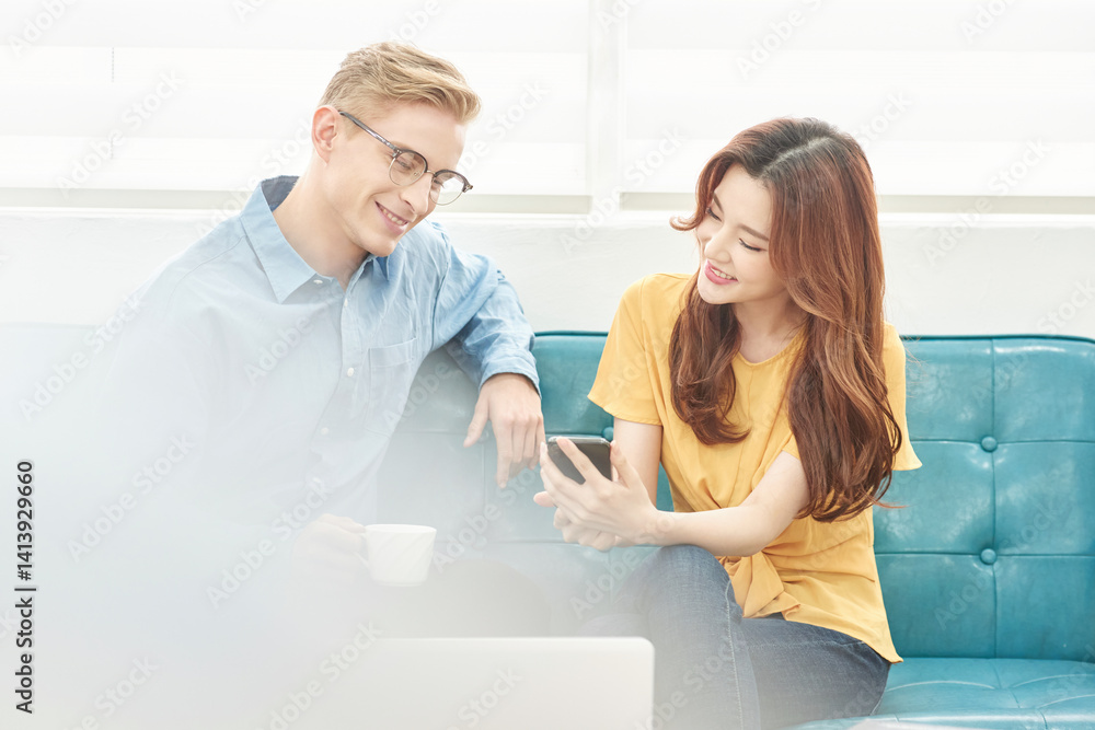 Obraz premium Multinational Man and Woman Having Conversation Indoors with Smartphone and Laptop