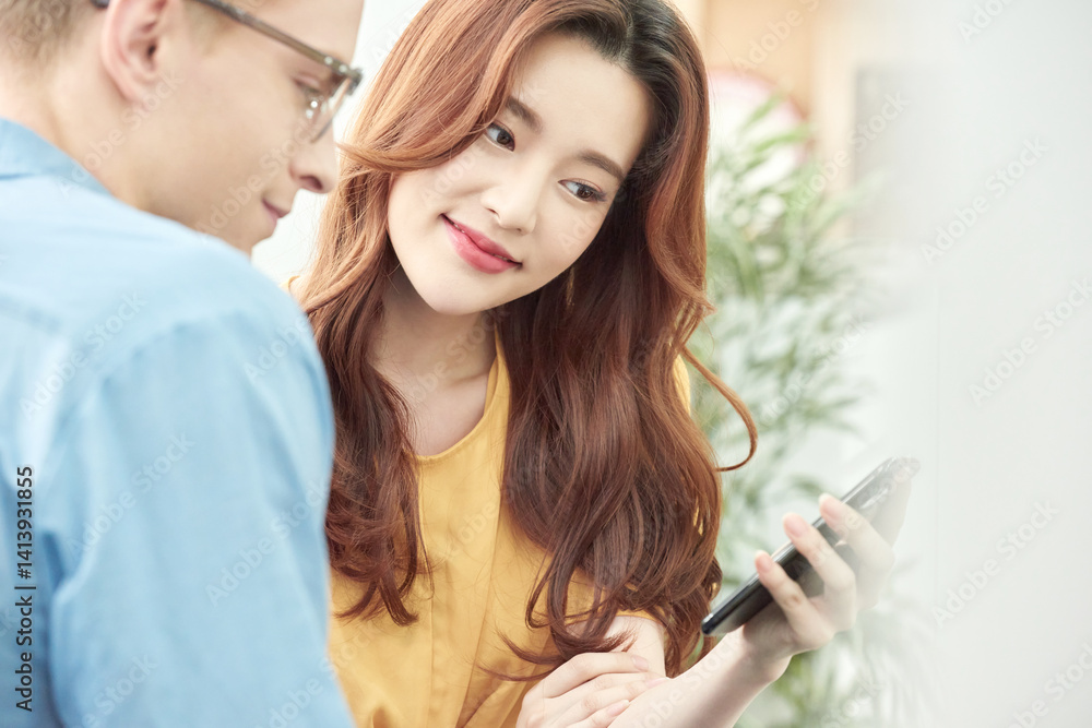 Multinational Man and Woman Discussing Indoors with Smartphone Multinational Man and Woman Discussing Indoors with Smartphone