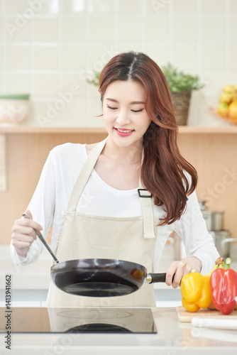 Smiling Asian Woman Cooking with Fresh Vegetables in Modern Kitchen