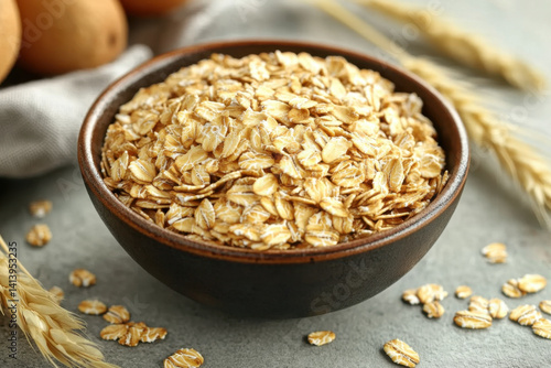 Bowl of oats beside scattered oats, wooden background.