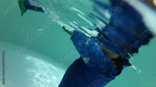 cute boy swimming into the pool, surface of water with sunlight