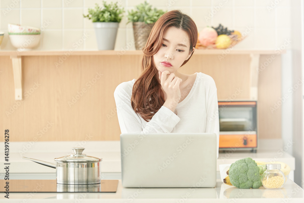 Young Woman Cooking and Using Laptop in Modern Kitchen Young Woman Cooking and Using Laptop in Modern Kitchen