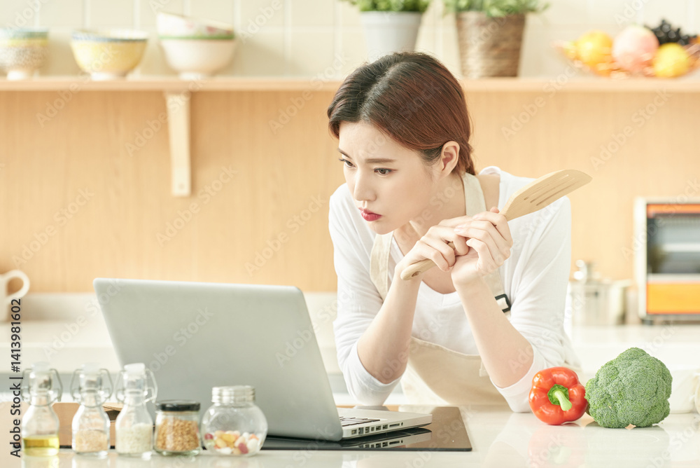 Young Woman Cooking at Home Using Laptop Young Woman Cooking at Home Using Laptop