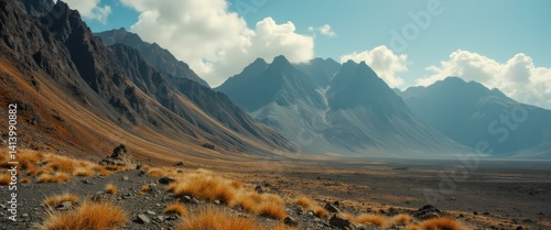Obraz na płótnie Dramatic mountains landscape scene of jagged peaks, rocky terrain, golden grasses under a blue sky with scattered clouds w salonie
