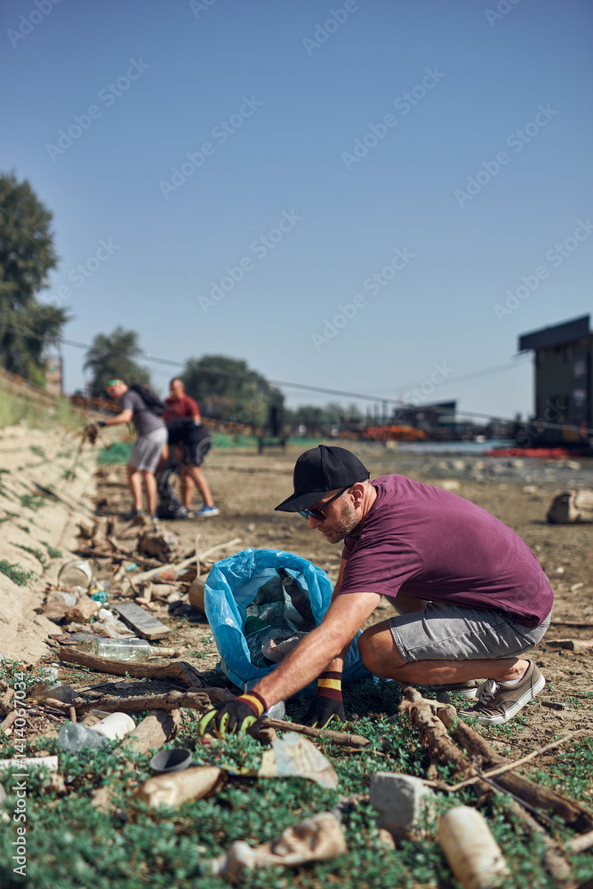 Environmental activist cleaning river shore from piled up trash.
