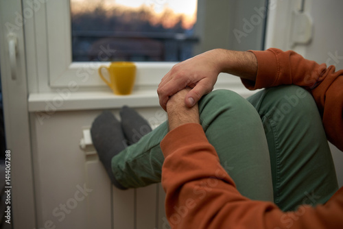 Man's feet with socks on a home heating radiator on a cold winter day outdoors.