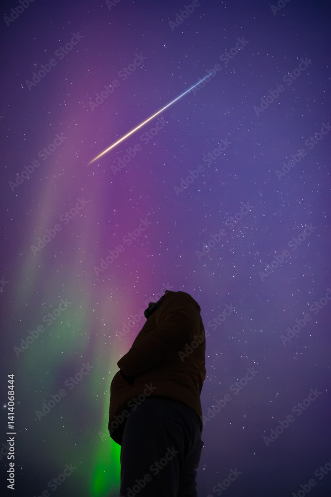 Man observing aurora borealis polar lights and Milky Way Stars from a dark countryside location.