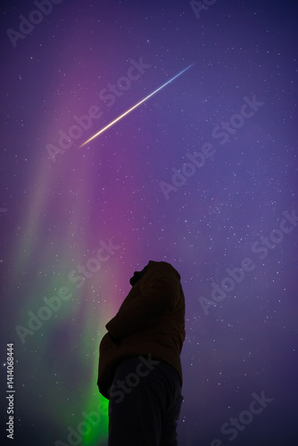 Man observing aurora borealis polar lights and Milky Way Stars from a dark countryside location.