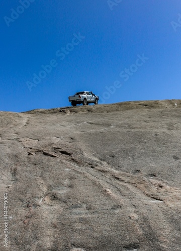 A four-wheel drive vehicle on top of a steep granite hill.