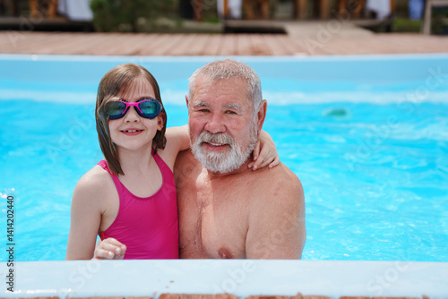Obraz na płótnie A grandfather and granddaughter play and swim in an outdoor pool. w salonie