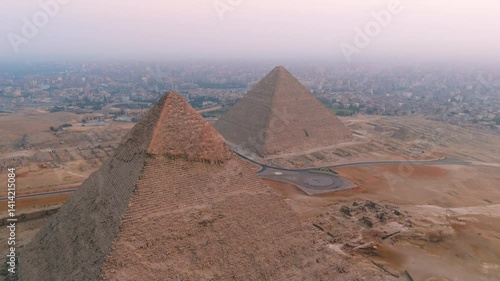 Pyramid Of Khafre And The Great Pyramid Of Giza With Foggy Background. Giza Pyramid Complex In Cairo, Egypt. aerial orbiting shot