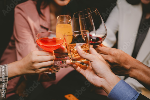 Cheerful group of stylish adults toast with whiskey at a luxurious bar, enjoying nightlife, friendship, and a festive celebration.