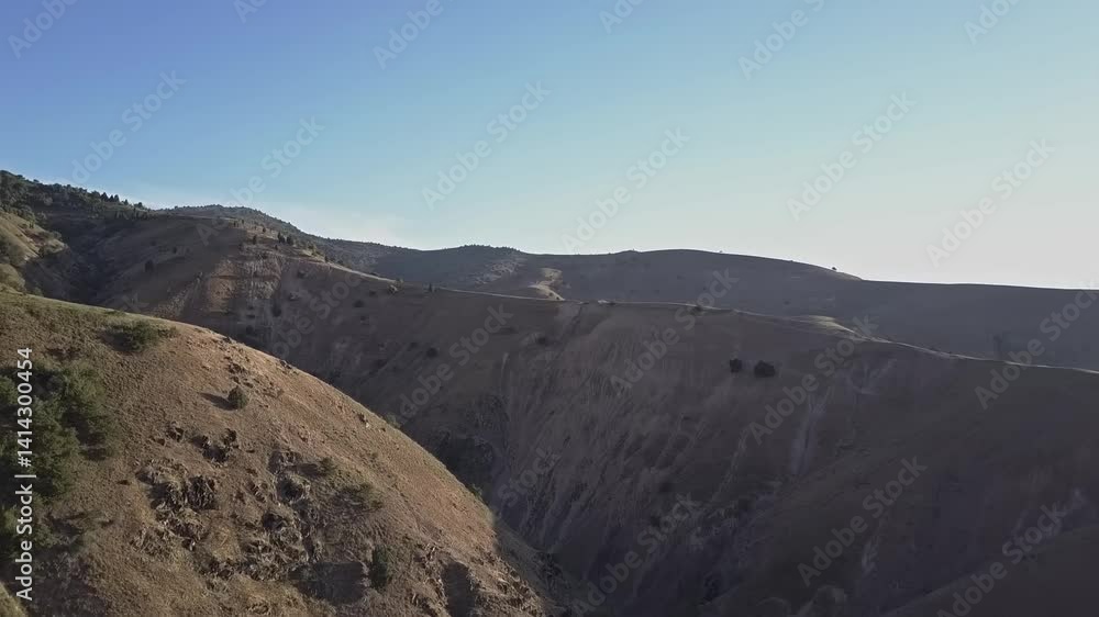 A drone flies over a mountain canyon with a river. The sun rises over the mountains. A cloudless summer morning. A drone flies over a mountain canyon with a river. The sun rises over the mountains. A cloudless summer morning.