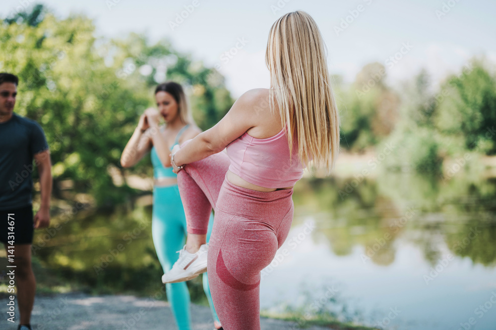 A group of friends exercising outdoors in a park, surrounded by lush greenery and a serene water body. They focus on fitness, health, and enjoyment in a natural environment. A group of friends exercising outdoors in a park, surrounded by lush greenery and a serene water body. They focus on fitness, health, and enjoyment in a natural environment.