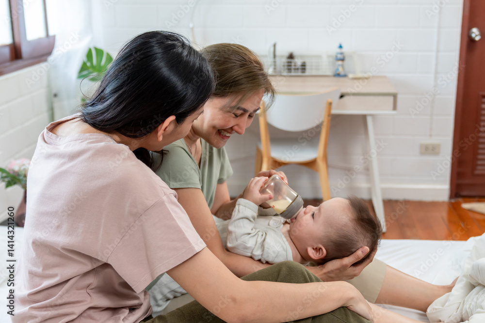 Obraz premium Asian lesbian couple caring for and raising their baby boy at home.