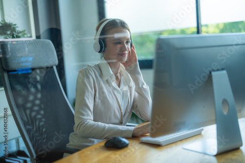Bilde på lerret Professional woman working at her desk with computer and headphones during a bri