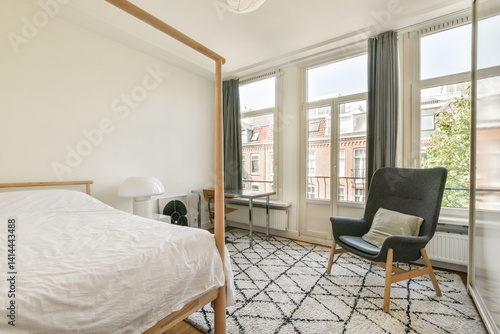 A bright  airy bedroom featuring a wooden bed  modern armchair  and natural light streaming through large windows  creating a serene atmosphere.