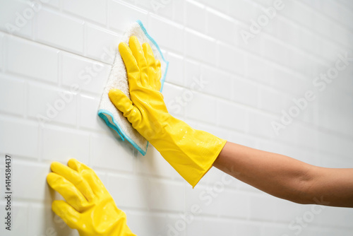 female house cleaner working cleaning wall wearing gloves using rag. housekeeper service doing chores disinfect and wipe kitchen surface with towel. professional housework staff woman cleaning wall
