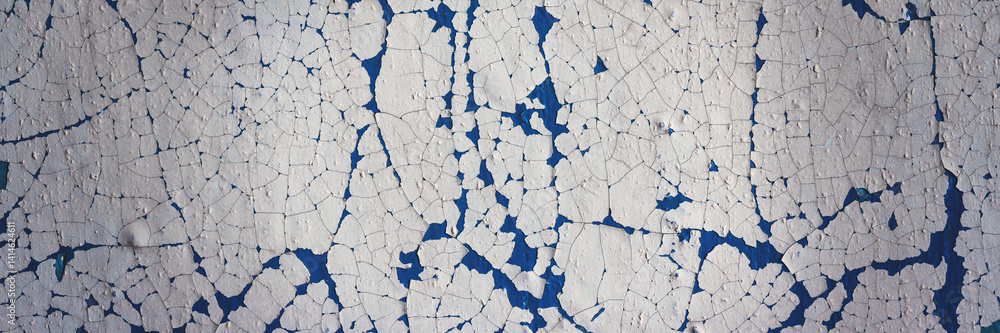 Peeling paint on the wall. Panorama of a concrete wall with old cracked flaking paint. Weathered rough painted surface with patterns of cracks and peeling. Wide panoramic texture for grunge background