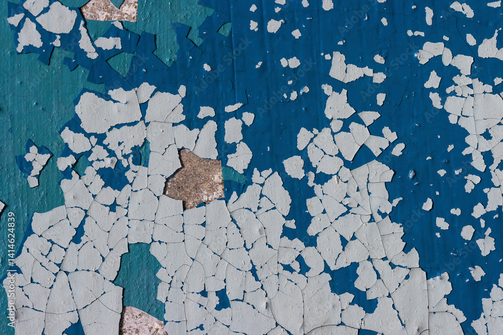 Peeling paint on the wall. Old concrete wall with cracked flaking paint. Weathered rough painted surface with patterns of cracks and peeling. Grunge texture for background and design. High resolution.