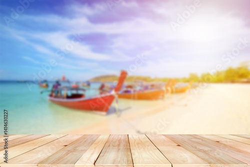 Wooden board empty table on the front with blurred line of Traditional Thai long-tail boat moor on the beach at the sea. Wooden for product or goods