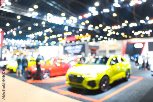Defocused blurry crowd anonymous people walking at exhibition trade fair at convention event or conference hall. light bokeh background.