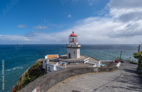 Farol do Arnel, der älteste Leuchtturm der Azoren, thront auf einem Felsvorsprung der Ponta do Arnel bei Nordeste, São Miguel. Weiß strahlend vor blauem Himmel und Meer, ein Symbol des Friedens.