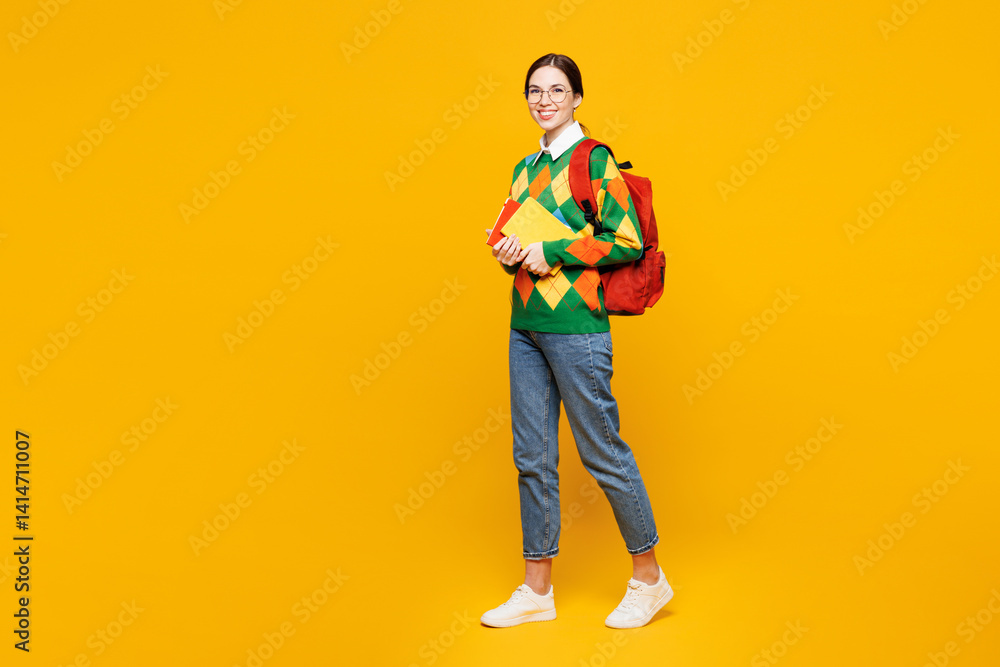 Fototapeta premium Full body side view young happy smart girl student she wears green casual clothes backpack bag hold books look camera isolated on plain yellow background studio High school university college concept