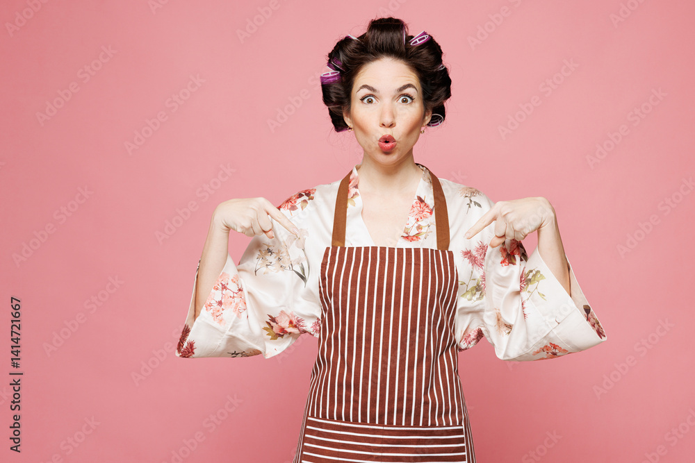 Young shocked housewife housekeeper chef cook baker woman wear brown apron point index finger down on area mock up isolated on pastel light pink color background studio portrait. Cooking food concept. Young shocked housewife housekeeper chef cook baker woman wear brown apron point index finger down on area mock up isolated on pastel light pink color background studio portrait. Cooking food concept.