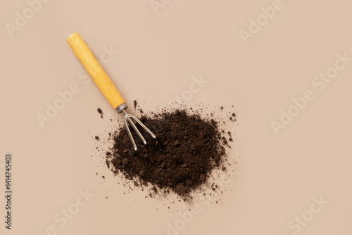 Concept season work and hobby. Various hand tools, plant and soil on beige background. Spring gardening. Top view.