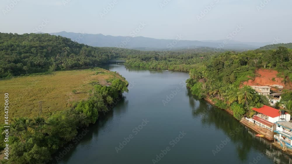 A stunning drone view of a serene lake in Goa, India, lush green trees on both side and majestic mountains. The still water mirrors the vibrant landscape, creating a peaceful, dreamlike scene A stunning drone view of a serene lake in Goa, India, lush green trees on both side and majestic mountains. The still water mirrors the vibrant landscape, creating a peaceful, dreamlike scene