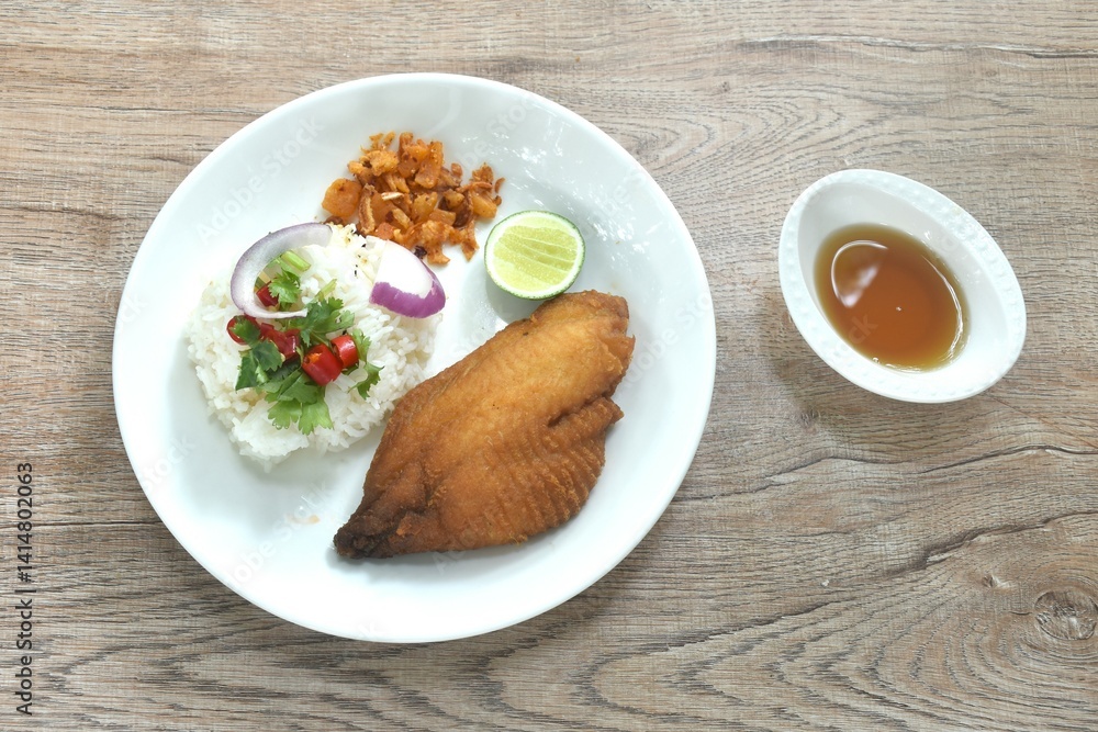 deep fried slice bass fish with rice topping chili and shallot dressing sweet fish sauce on plate