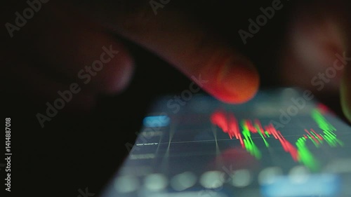 Wallpaper Mural Man reads a stock market chart on his mobile phone while trading online. Trader working with a mobile application, dark background, close-up Torontodigital.ca