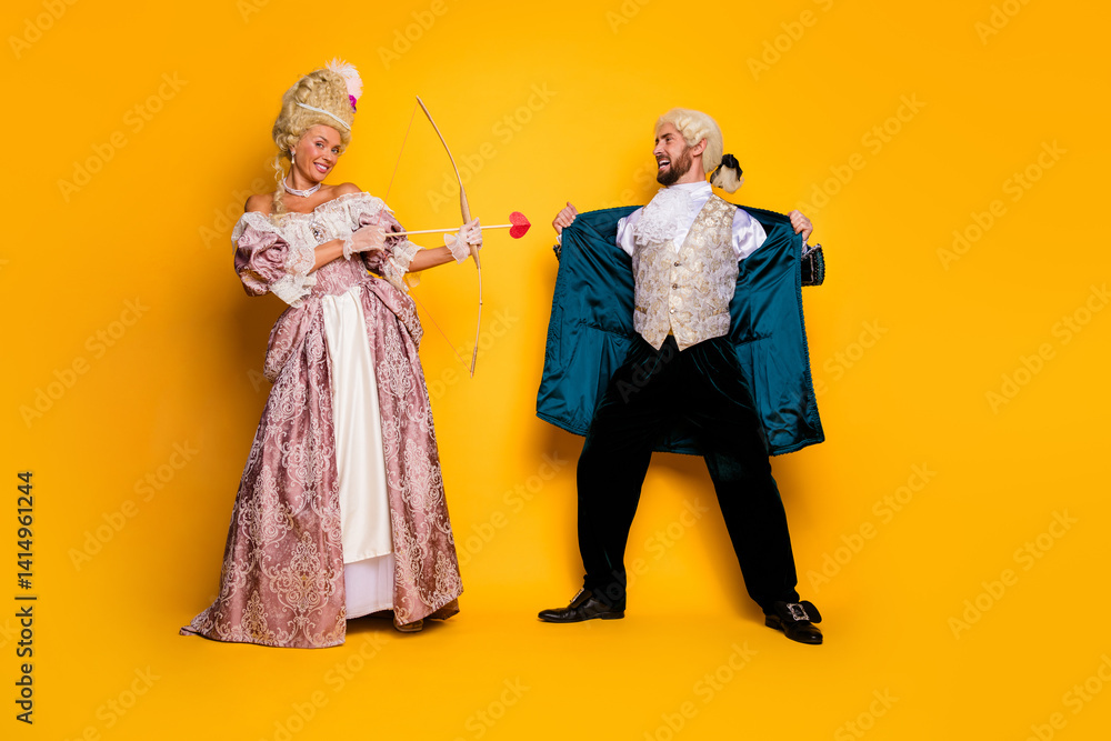 Fototapeta premium Playful couple in vintage costumes enjoying themed photoshoot on colorful yellow backdrop