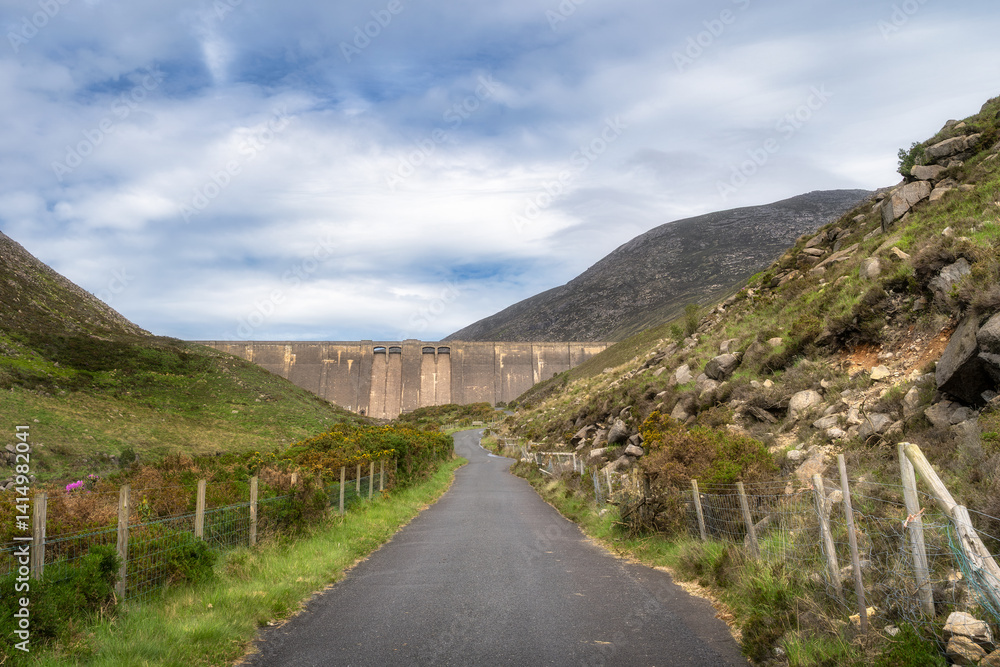 Take delight in serene walk along meandering path that leads to breathtaking dam in Silent Valley Reservoir, set amidst gently rolling hills and vibrant scenery beneath stunning sky, Northern Ireland Take delight in serene walk along meandering path that leads to breathtaking dam in Silent Valley Reservoir, set amidst gently rolling hills and vibrant scenery beneath stunning sky, Northern Ireland