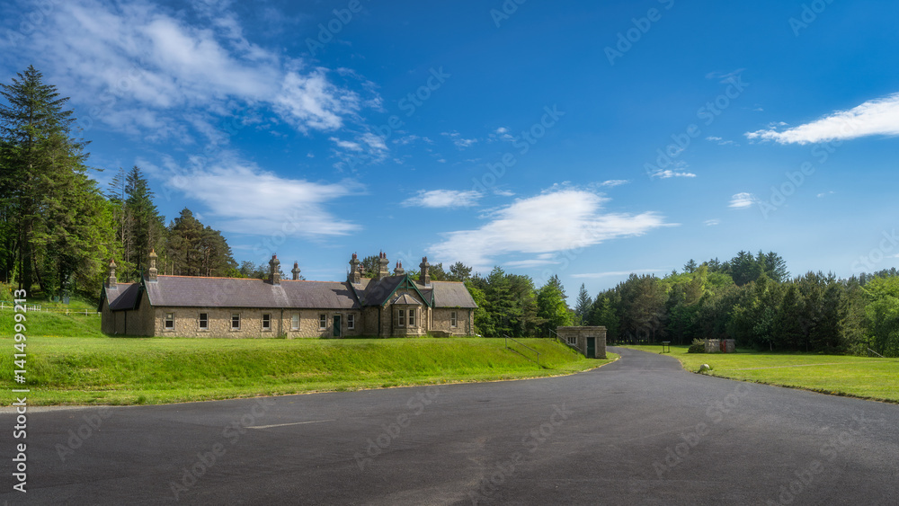 A picturesque scene featuring a classic stone building of Silent Valley Reservoir against a vibrant green landscape and clear blue skies, perfect for nature lovers and explorers, Northern Ireland
