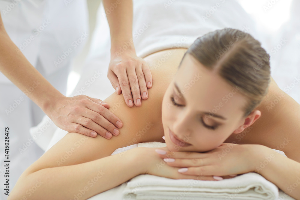 Closeup of relaxed happy smiling woman enjoying professional body massage in modern spa salon. Masseuse massaging back of female person lying on couch. Beauty day and wellness concept. Closeup of relaxed happy smiling woman enjoying professional body massage in modern spa salon. Masseuse massaging back of female person lying on couch. Beauty day and wellness concept.