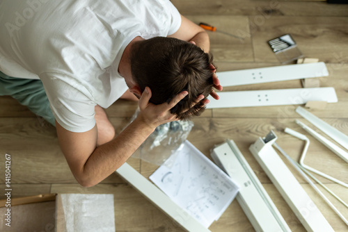 Bilde på lerret man clutches his head looking at furniture assembly diagram