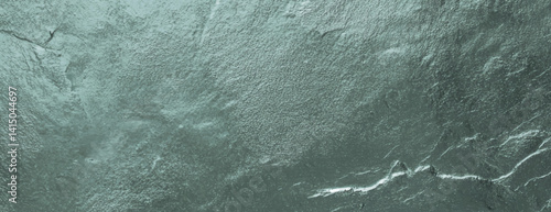 Green textured stone background with a rough, natural feel. The background features a green hue with a rugged texture. Textured stone background vector. Green background.