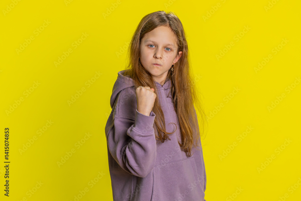 Aggressive angry young preteen child girl kid trying to fight at camera, shaking fist, boxing with expression, punishment, threaten, bullying, abuse, mad fury. Children isolated on yellow background Aggressive angry young preteen child girl kid trying to fight at camera, shaking fist, boxing with expression, punishment, threaten, bullying, abuse, mad fury. Children isolated on yellow background