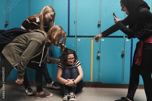 Bild auf Leinwand Group of teens bullying a girl in front of lockers