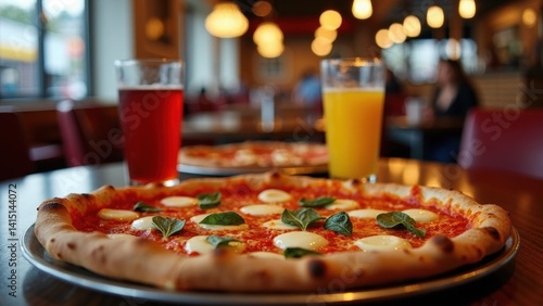 Obraz na płótnie Pizza with cheese and basil sits on a table next to two glasses of orange juice. The scene is casual and inviting, with the pizza w salonie