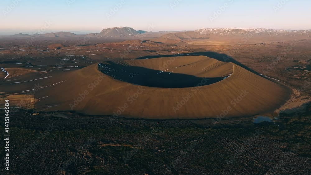 Aerial view of Hverfjall volcano in Iceland at sunset, highlighting the perfect circular shape of the crater in warm golden light. Aerial view of Hverfjall volcano in Iceland at sunset, highlighting the perfect circular shape of the crater in warm golden light.