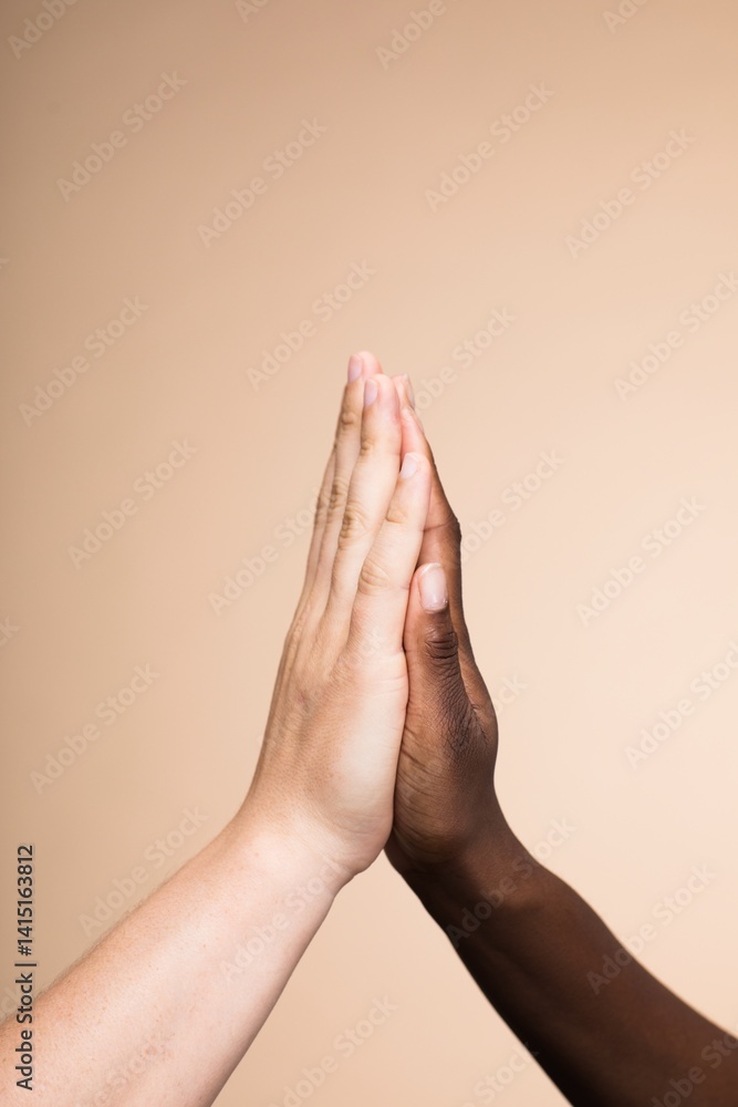 Two hands, of different skin color tones, high-fiving. Hands in unity, symbolizing diversity and teamwork. High-five gesture showing diversity and unity. Diversity and teamwork with high five.