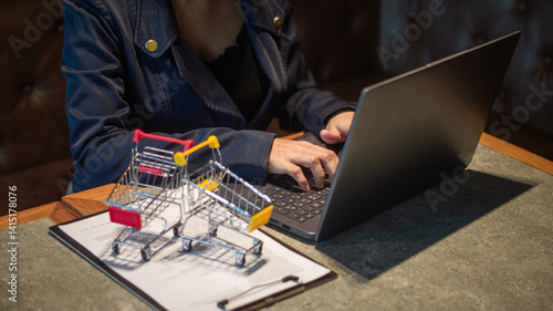 Wallpaper Mural Businesswoman working on laptop about selling products. In front of her are documents and a small cart. Online trading and shopping. Torontodigital.ca