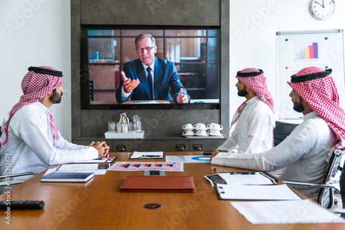 Canvas Print Arab businessmen wearing saudi kandura meeting in office for business deal - Cor