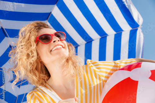 Canvas Print Happy young woman under a striped blue parasol